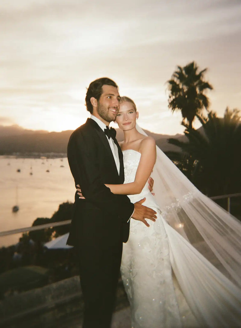 Couple in formal attire standing together with a scenic background