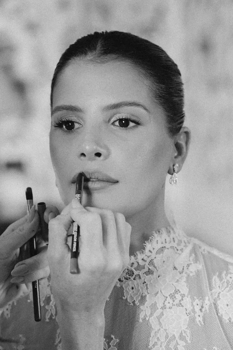 Black and white photo of a woman having lipstick applied