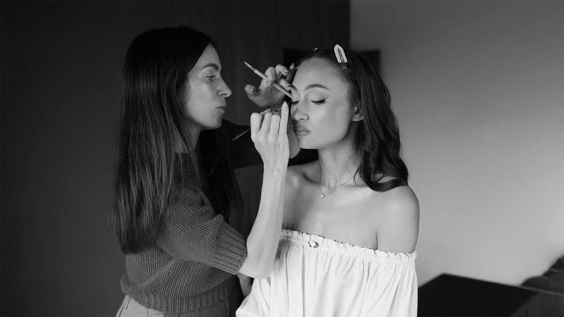 Black and white photo of a makeup artist Rebecca Spendlove applying makeup to a bride on her wedding day.