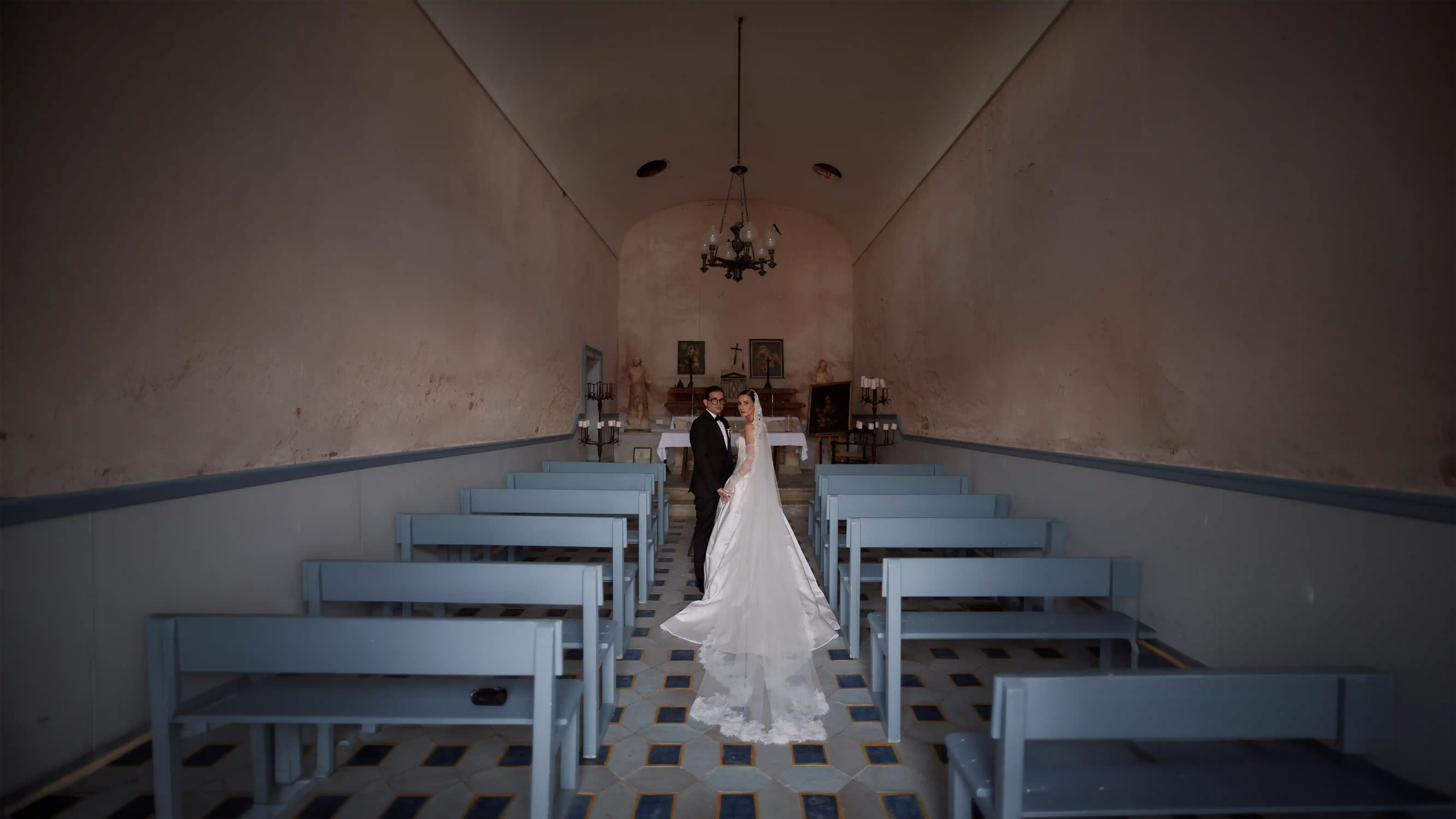 Wedding couple standing in a small church with blue benches.